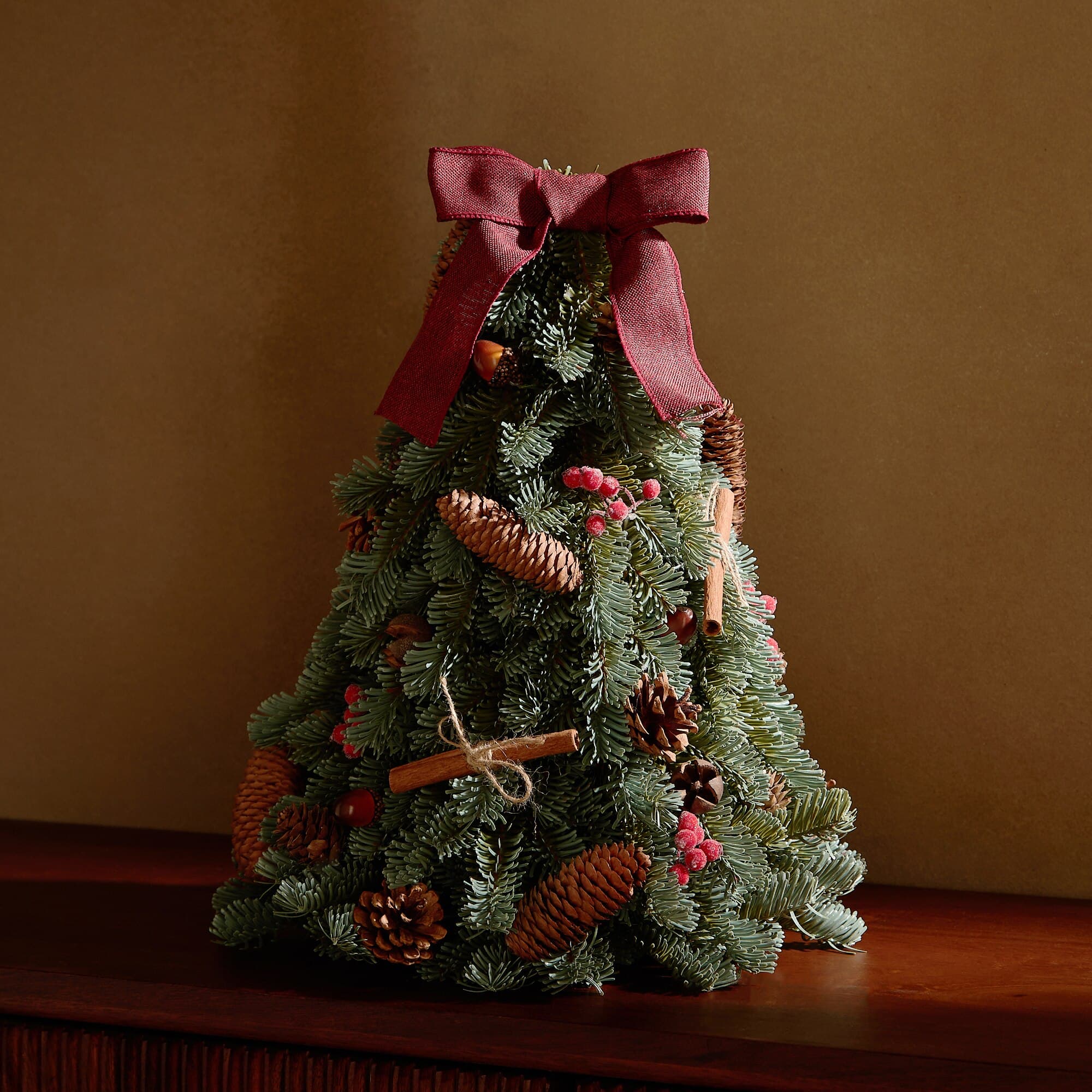 Árbol de Navidad de mesa decorado con piñas y lazo
