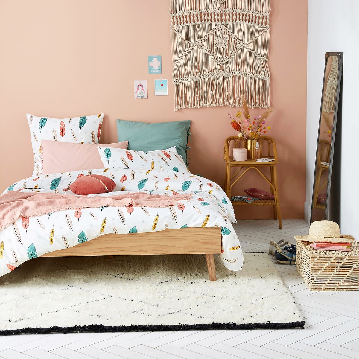 Cama de madera clara con ropa de cama estampada