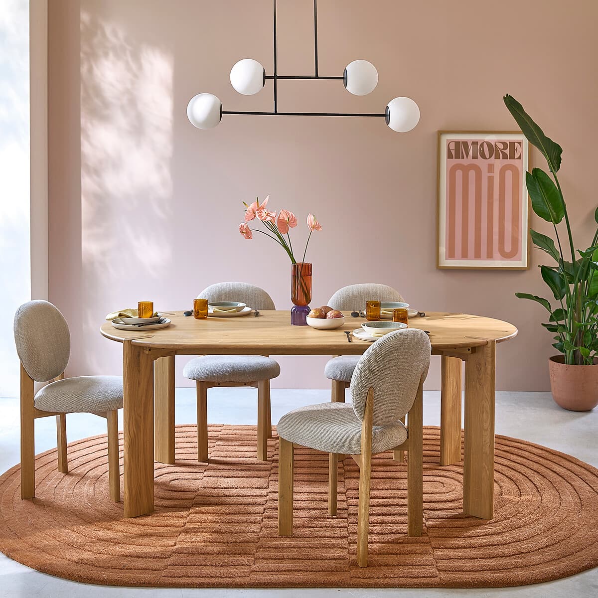 Mesa de comedor ovalada de madera clara y sillas a juego