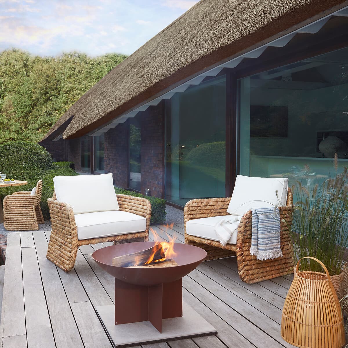 Sillón de exterior de ratán con cojines blancos